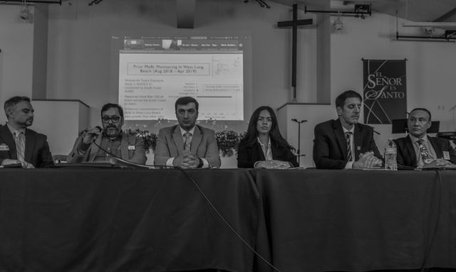 Black and white photo of six people sitting side by side at a table.