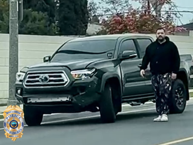 Blurry photo of a man in dark clothes standing next to a dark colored pickup truck.