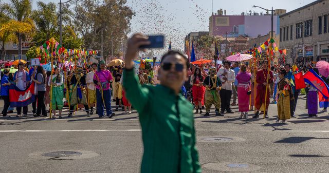 A man in a green shirt takes a picture of himself while he stands in the middle of the street. 