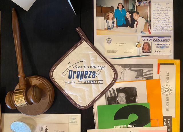 A collection of papers, photos, cards, a gavel and a potholder that says "Jenny Oropeza for City Council."