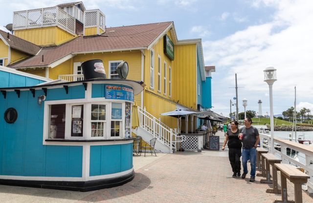Two people walk next to a bright blue building and a bright yellow building.