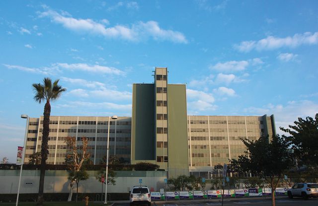 A large building set against a blue sky with wispy white clouds.