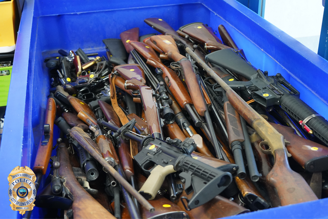A pile of rifles in a large blue bin.