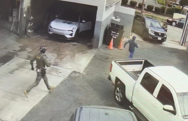 A masked man chases another man between two cars.