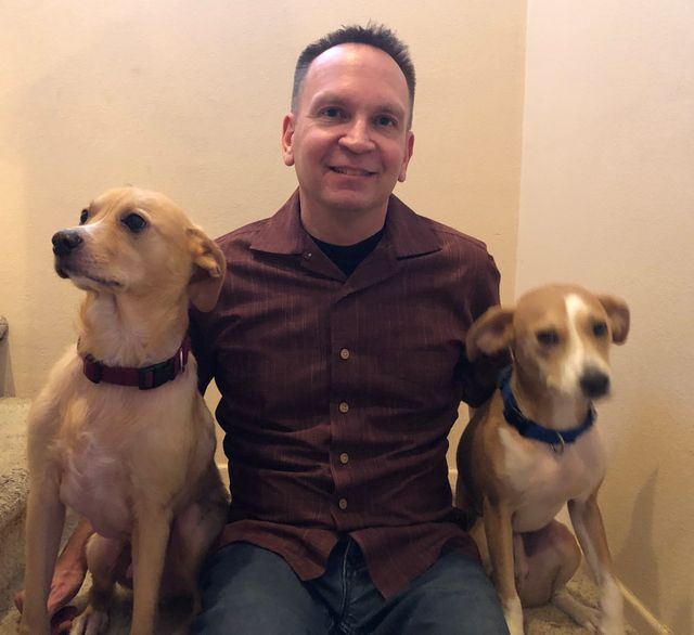 A man sits between two very good dogs.