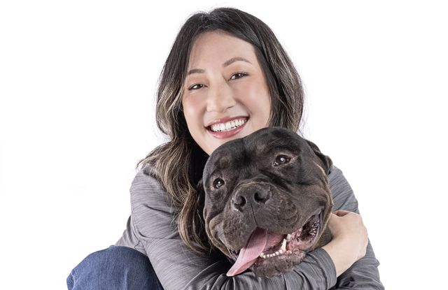  A woman smiles while hugging a lovable brown dog. 