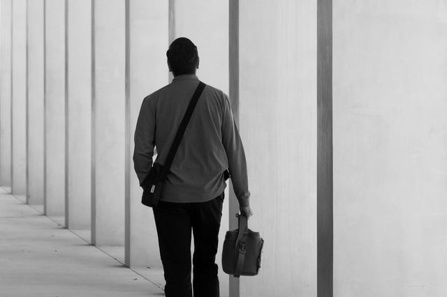 A man holding a small bag walks away.