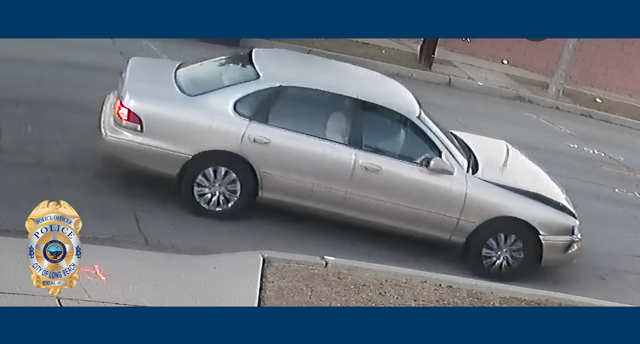 A slightly blurry photo a tan Toyota Avalon with damage to its hood and front end.