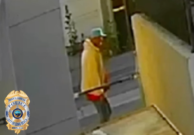 Blurred image of a man in a yellow hoodie, teal hat and jeans.