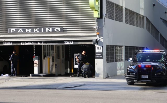 Three police officers and a police car are outside a parking garage