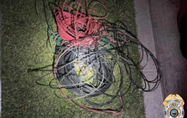 Slightly blurry image of coils of black, red and green wiring lying on grass at night.