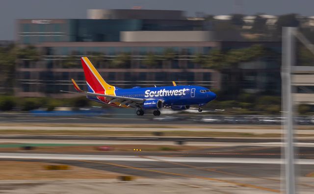 A commercial airliner with the word "Southwest" painted on the side lands at a very blurry airport.