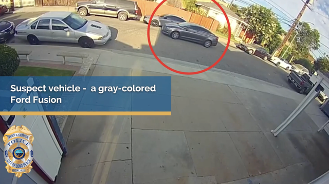 A red circle is drawn around a gray car traveling on a busy residential street next to the words "Suspect vehicle — a gray-colored Ford Fusion."