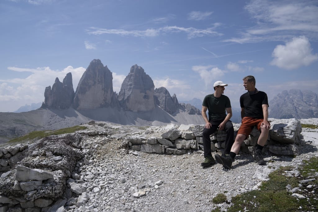 Uwe und Jannik Kreye sitzen auf einer Steinmauer vor den Drei Zinnen