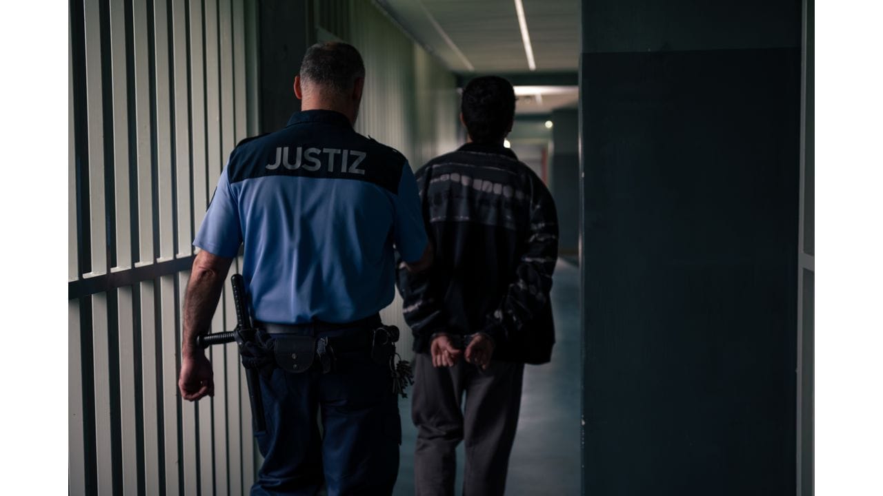 Justizbeamter führt einen Mann durch einen Gang, Szene aus Clangold