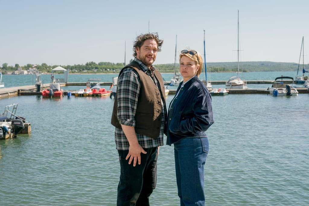 Ronald Zehrfeld und Jördis Triebel am Steg vor einem Hafen