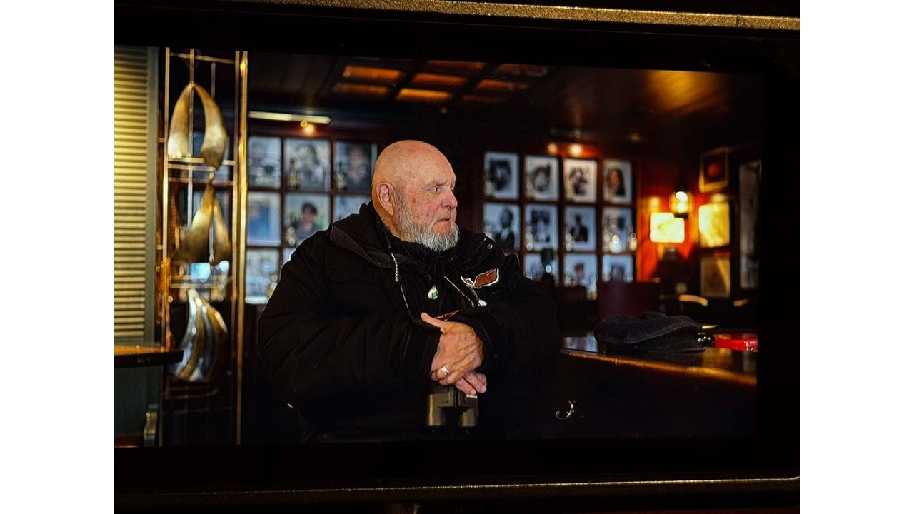 Älterer Mann sitzt in einer Bar, gesehen auf dem Monitor einer Filmkamera