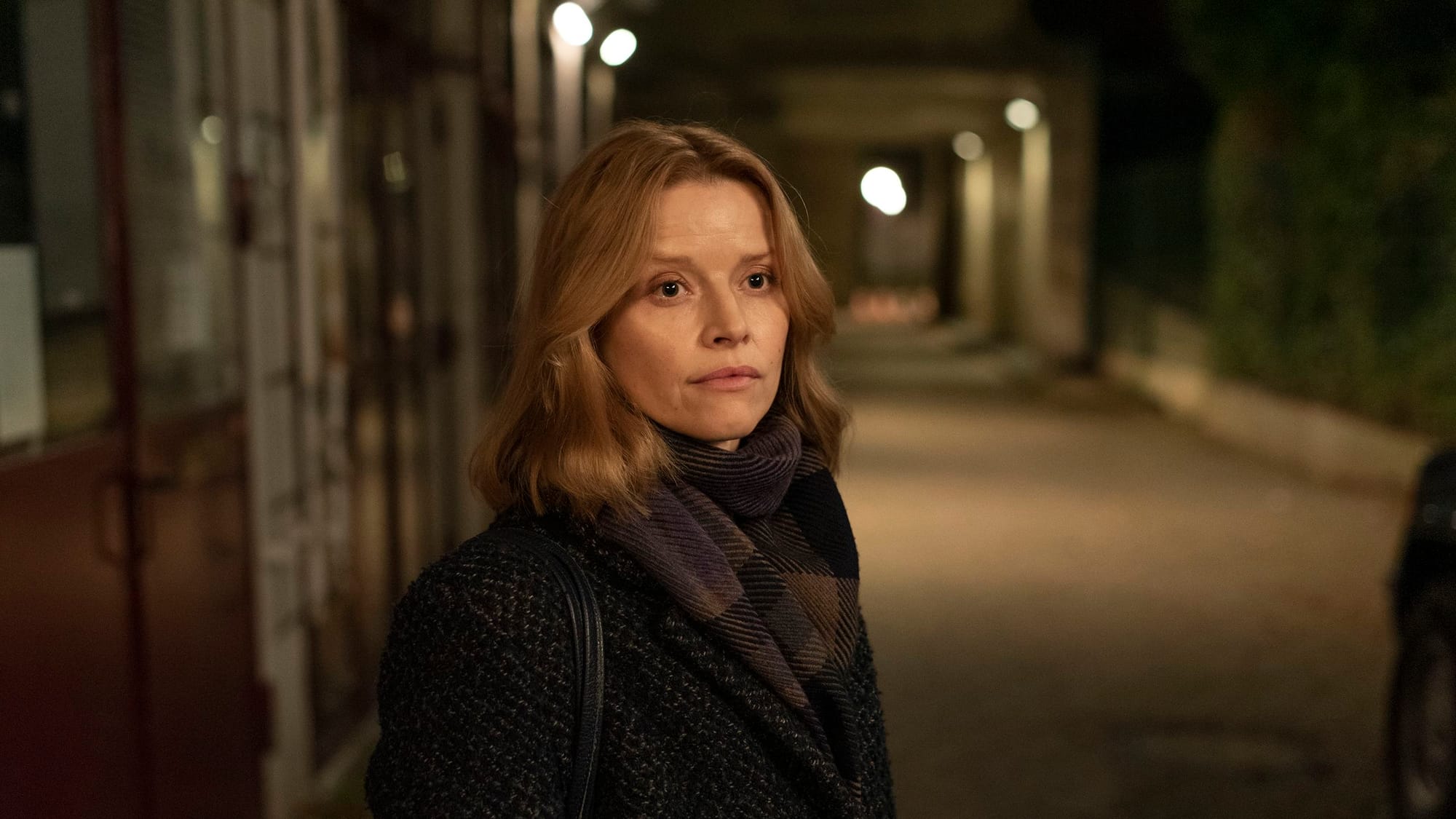 Eine Frau mit Schal in einer nächtlichen Gasse