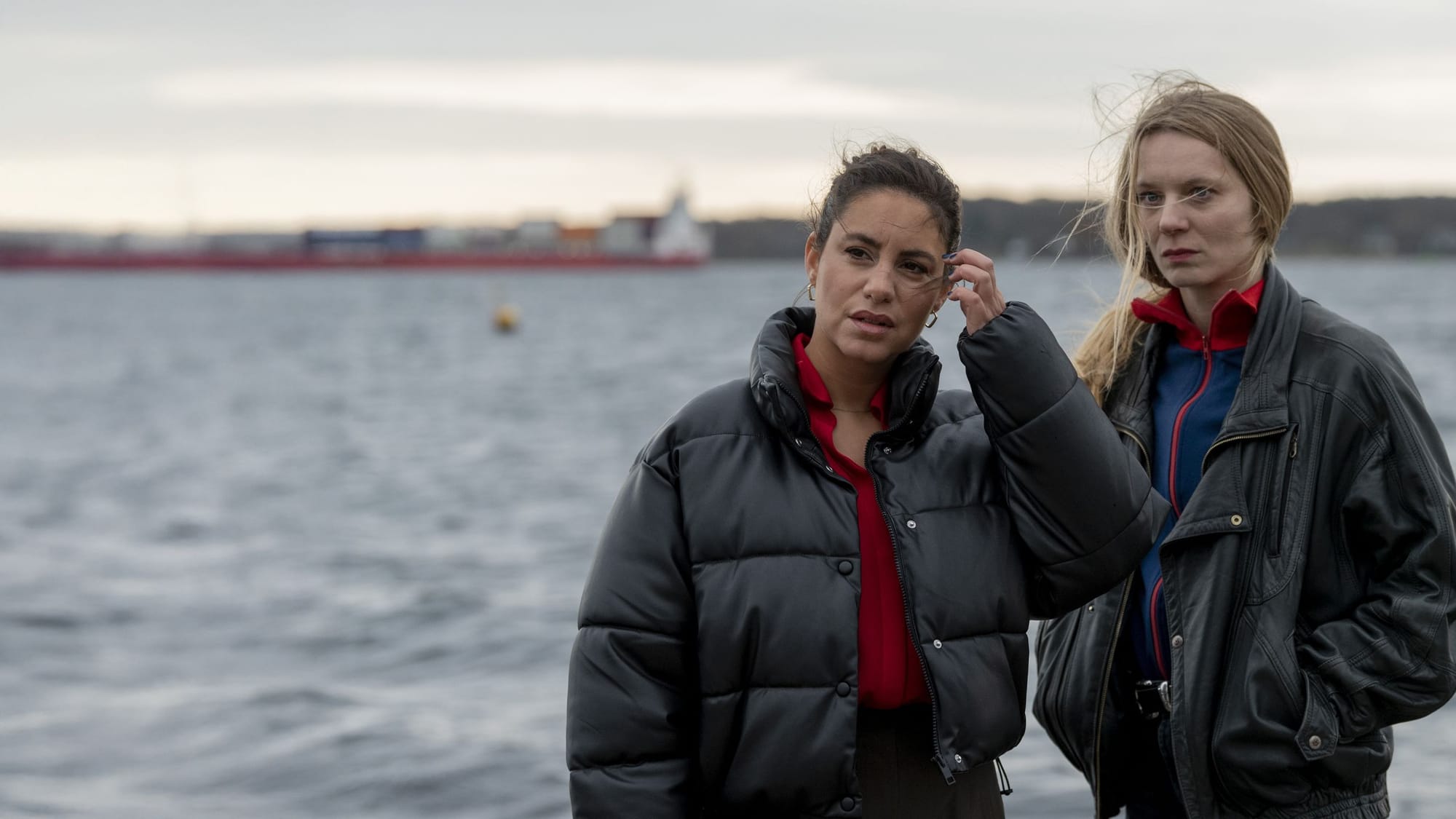 Zwei Frauen in dunklen Jacken stehen am Wasser