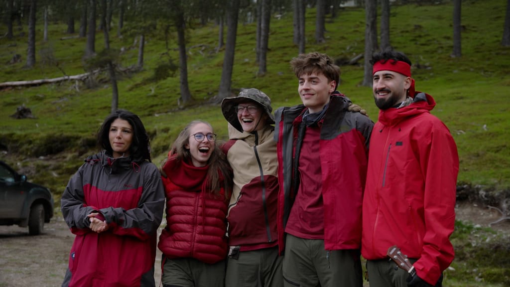 Fünf Creatorinnen und Creator in roten Jacken im Wald