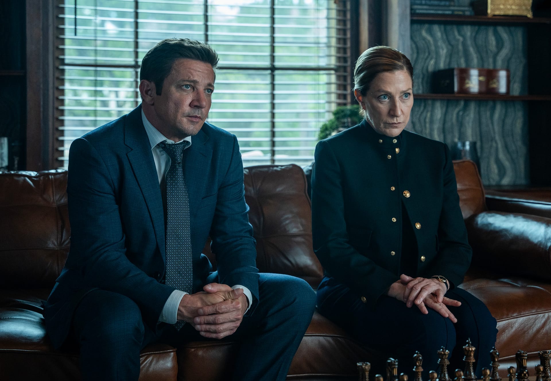 Jeremy Renner und Edie Falco auf einem Ledersofa in Mayor of Kingstown