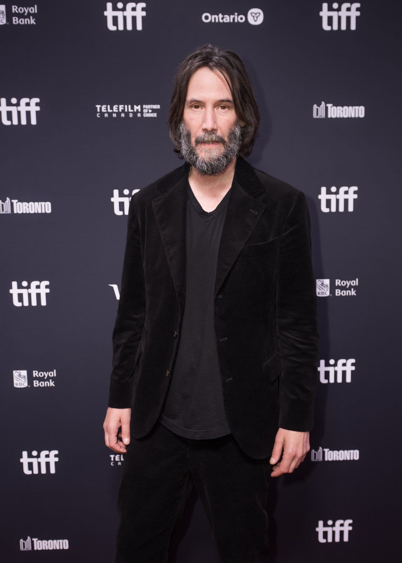 Keanu Reeves in schwarzem Samtjackett vor der Pressewand des Filmfestivals Toronto