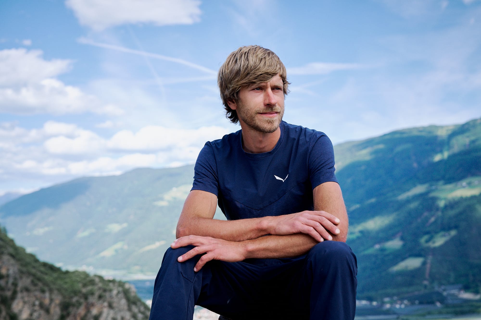 Simon Messner sitzt vor einem Bergpanorama