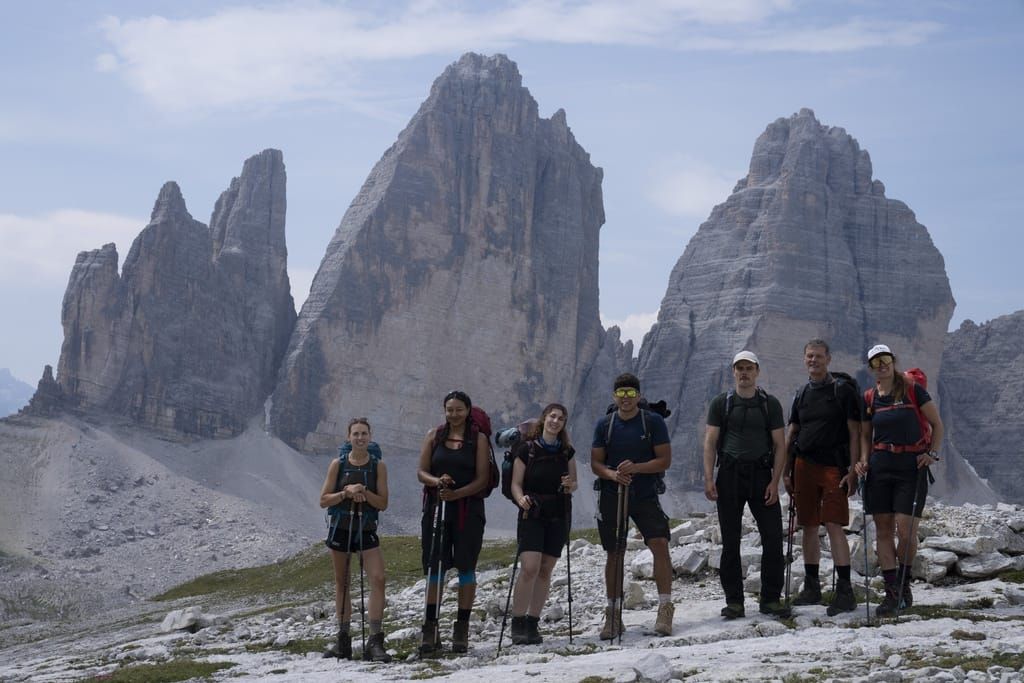 Die Wandergruppe steht vor den Drei Zinnen in den Dolomiten