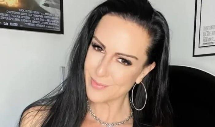 Texas Patti mit langen schwarzen Haaren und Creolen vor einem Filmplakat