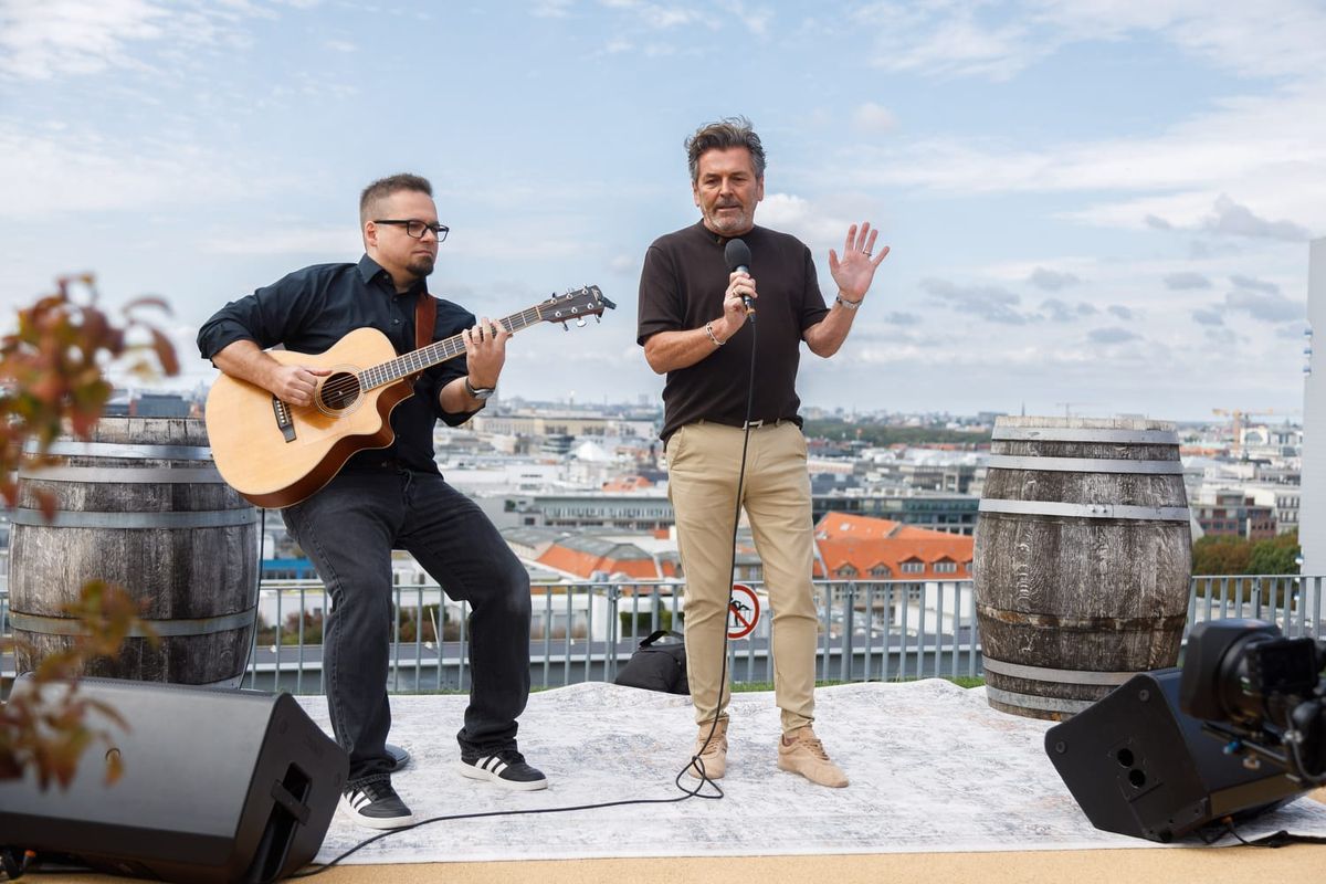 Thomas Anders singt mit Mikrofon auf einer Dachterrasse in Berlin, neben ihm ein Gitarrist