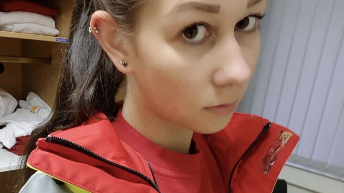 Lia Sommer in roter Rettungsdienstjacke mit Warnstreifen beim Selfie im Umkleideraum