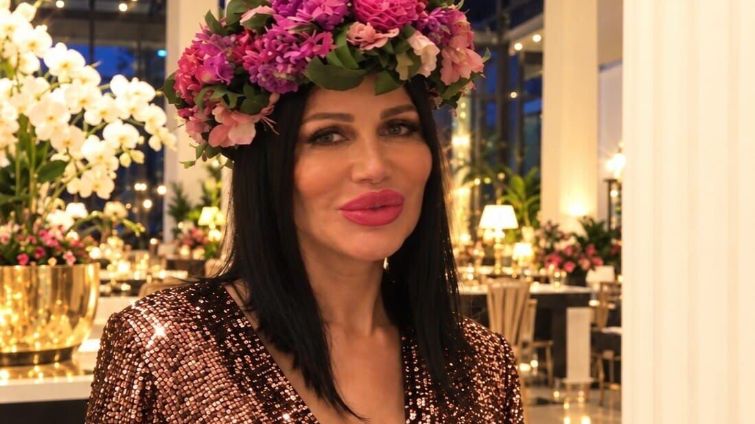 Djamila Rowe im Paillettenkleid mit Blumenkranz in einer festlich beleuchteten Halle