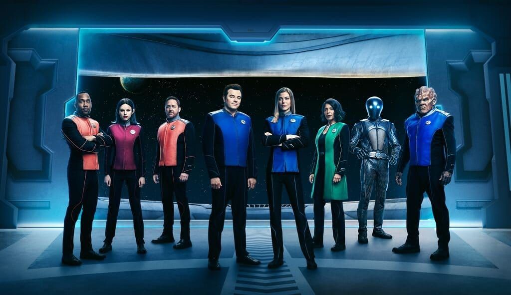 Cast von The Orville in Uniformen vor dem Raumschifffenster, u. a. Seth MacFarlane und Adrianne Palicki