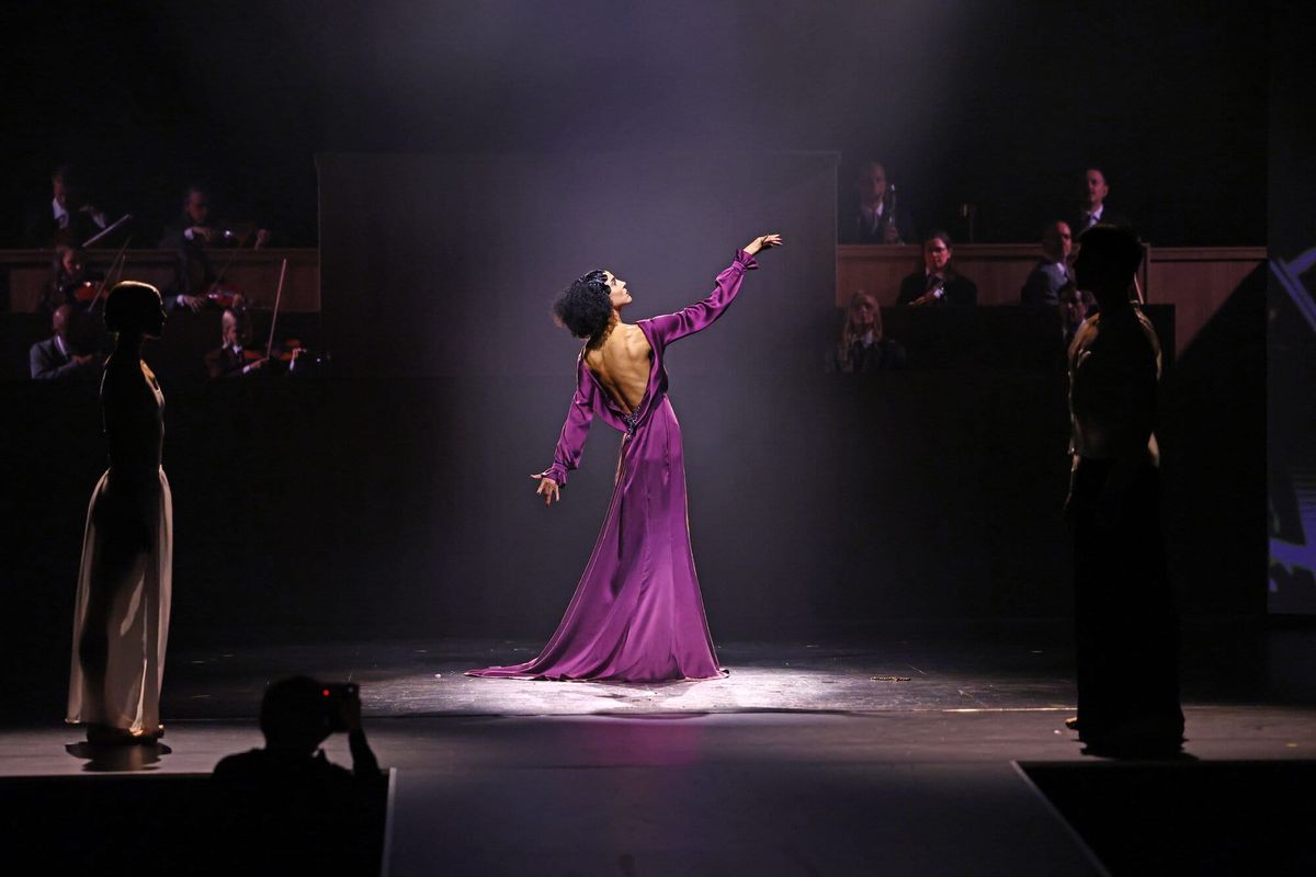 Bühnenszene der ABOUT YOU Fashion Show im Berliner Admiralspalast: Tänzerin im violetten Kleid im Spotlight, dahinter das Orchester