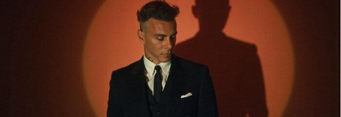 Asaf Avidan im dunklen Anzug vor orangem Spotlicht