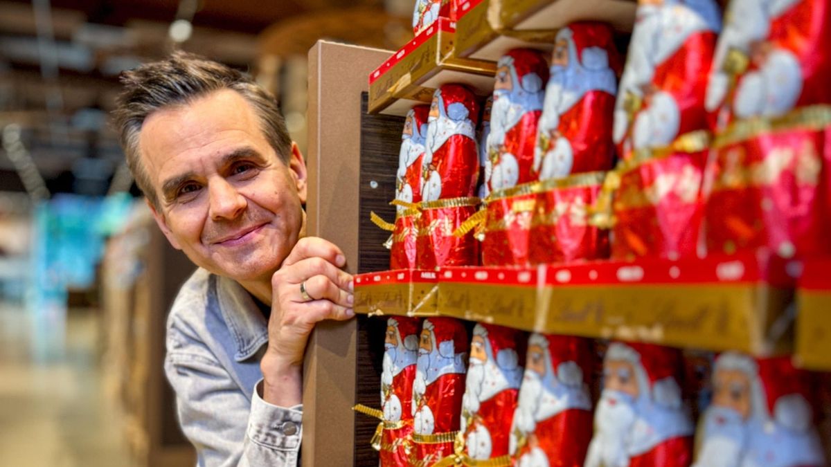 Reporter Stefan Uhl schaut zwischen Regalen mit Schokoladen-Weihnachtsmännern hervor