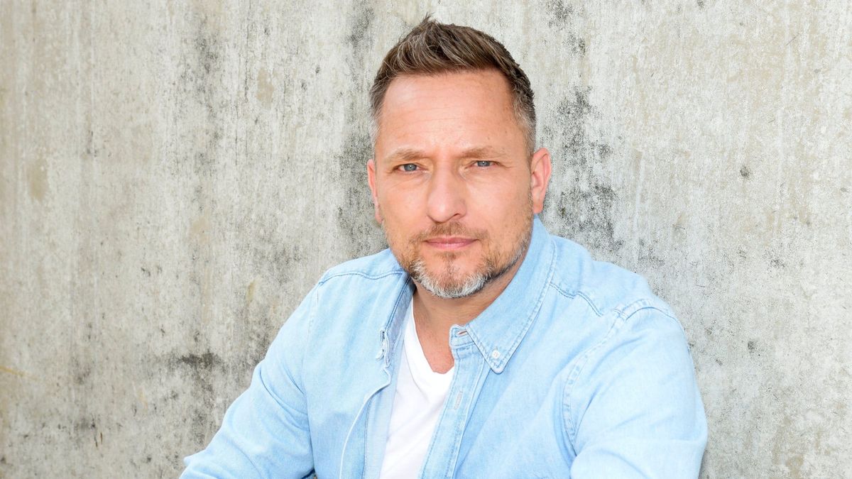 Lars Pape im hellblauen Hemd vor einer Betonwand