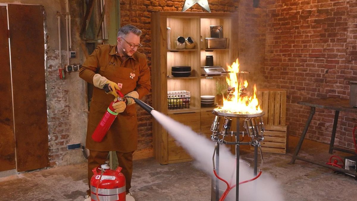 Sebastian Lege mit Feuerlöscher vor einer Stichflamme im Lege Lab