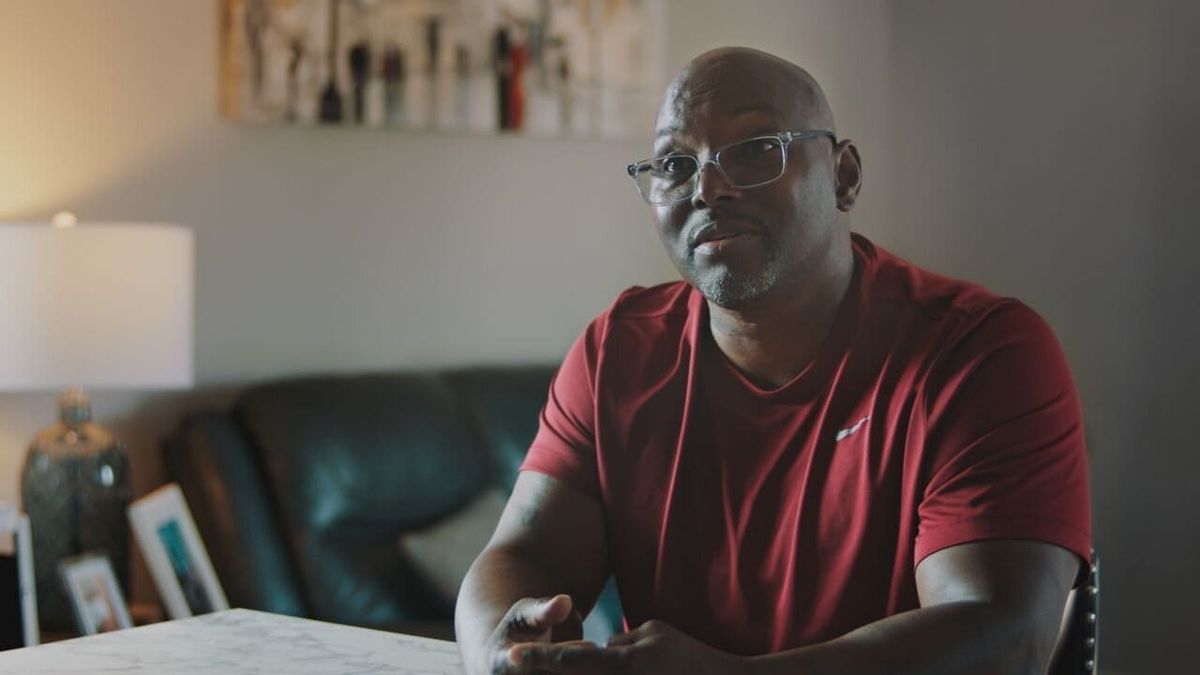 Filmstill aus der HBO-Dokumentation „When a Witness Recants“: Mann mit Brille im roten T-Shirt im Interview am Tisch