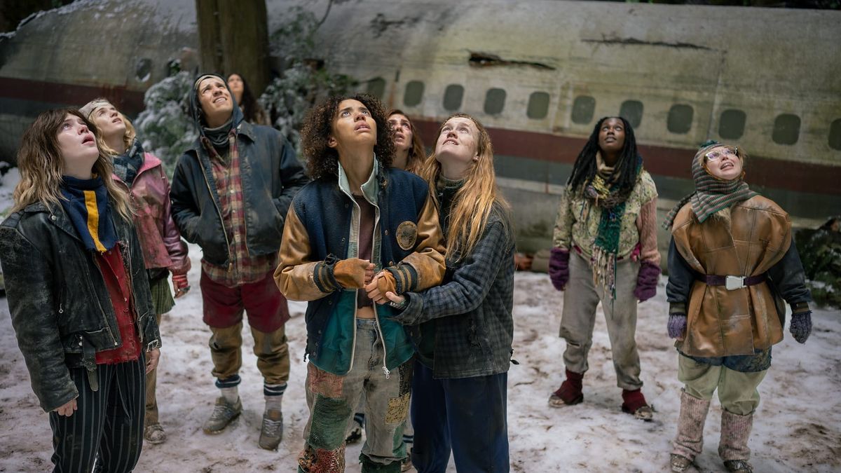 Das Teen-Ensemble von Yellowjackets vor einem Flugzeugwrack im Schnee