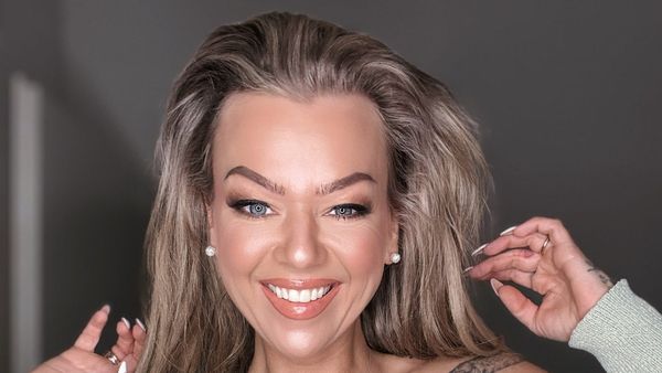 Doreen Steinert lächelt in die Kamera und fährt sich mit beiden Händen durchs Haar