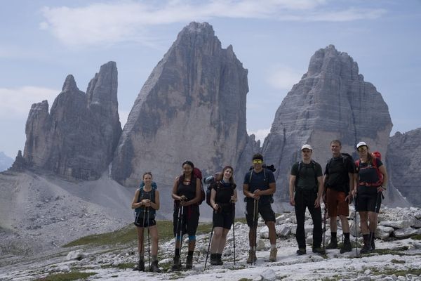Die Wandergruppe steht vor den Drei Zinnen in den Dolomiten
