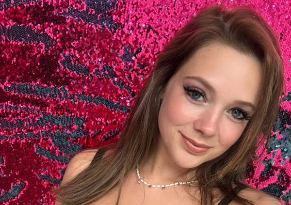 Anne Wünsche im schwarzen Top vor einer pinkfarbenen Paillettenwand