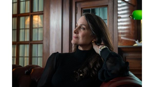 Carrie-Anne Moss im schwarzen Pullover in einem holzgetäfelten Raum, Szene aus "Yaga"