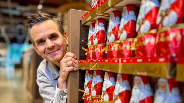 Reporter Stefan Uhl schaut zwischen Regalen mit Schokoladen-Weihnachtsmännern hervor