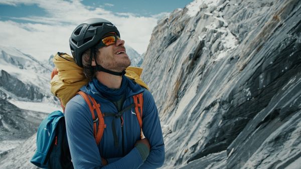 Simon Messner mit Helm und Rucksack vor einer Felswand