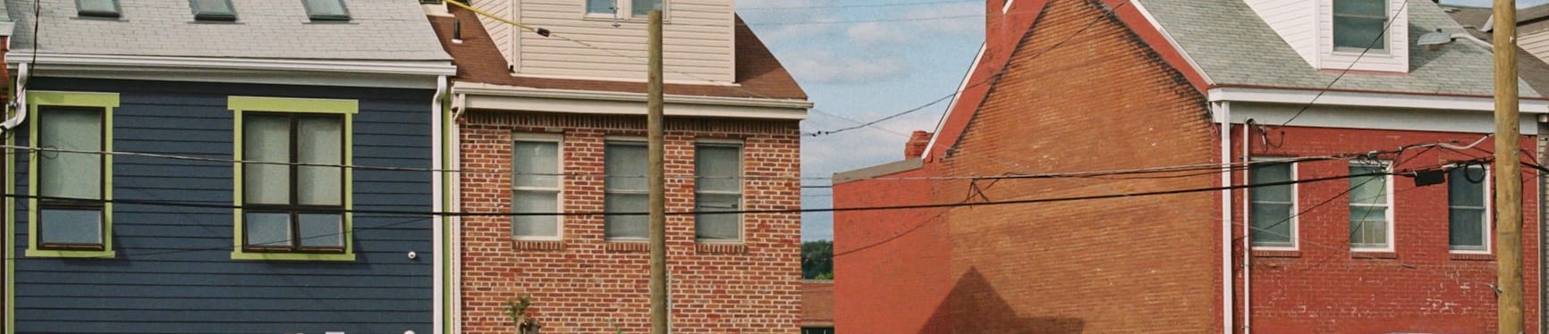 A parking lot with a fence in front of a row of houses