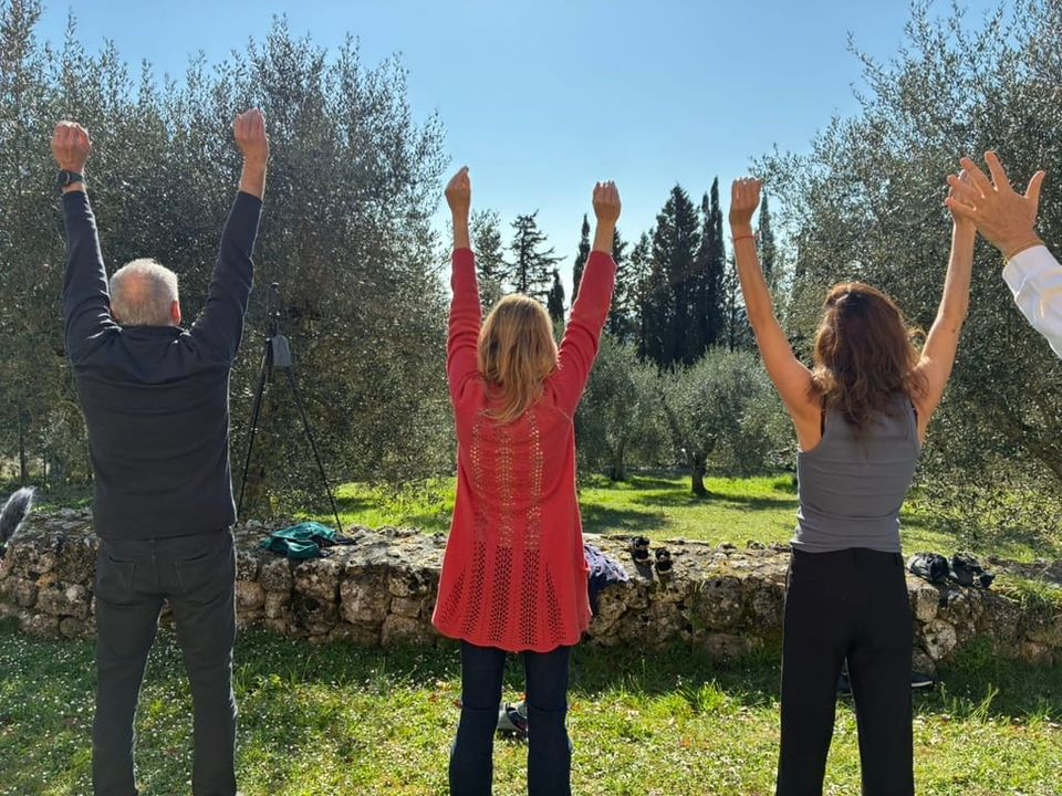 Three people hold their arms above their heads, with a fourth just out of frame. 