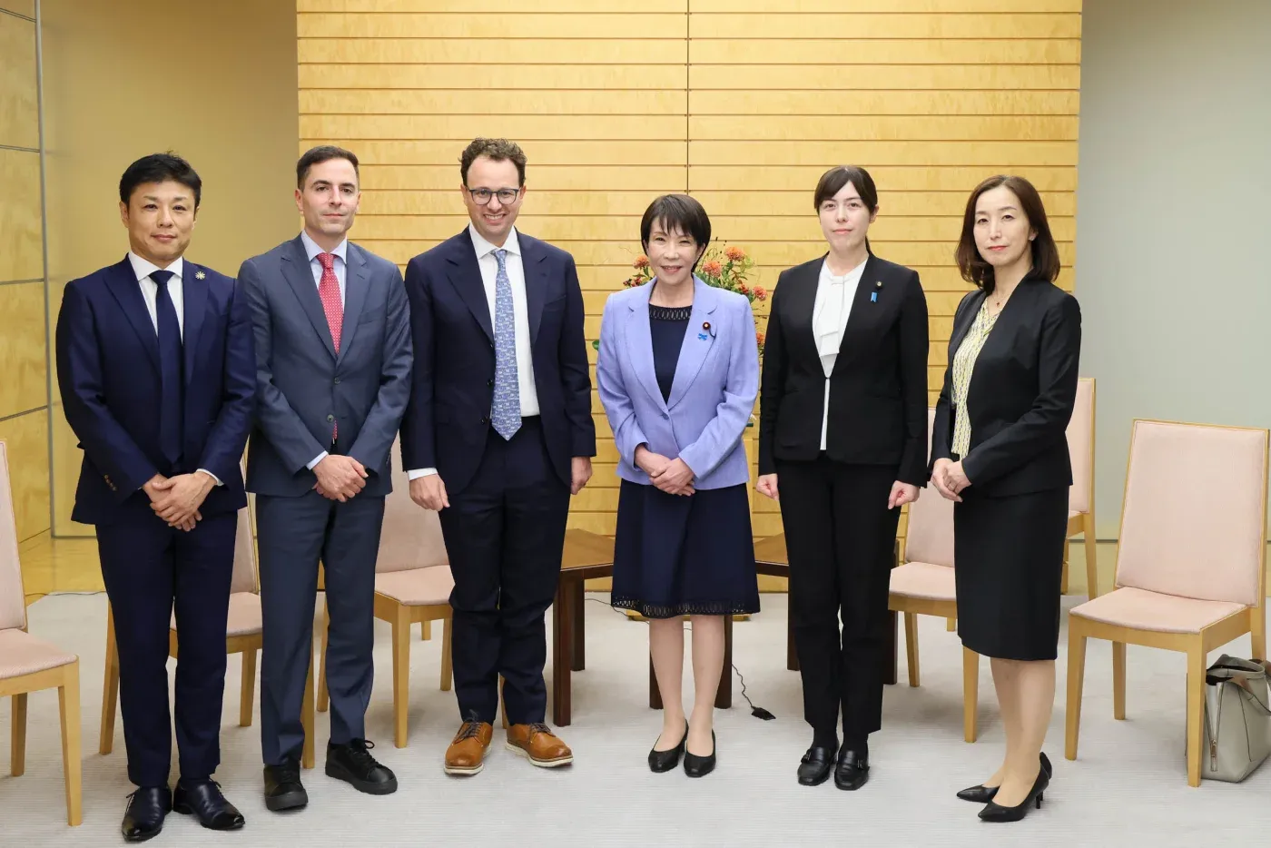Sex personer står på rad i ett rum med ljusa träväggar. Dario Amodei, tredje från vänster, står bredvid Japans premiärminister Sanae Takaichi i ljuslila kavaj