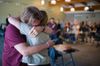 Two people embracing, in front of a crowd giving a standing ovation.